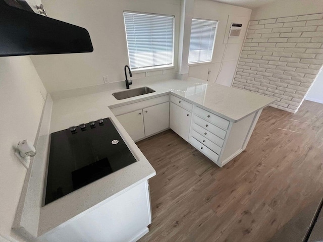 kitchen featuring sink, white cabinetry, black electric stovetop, extractor fan, and kitchen peninsula