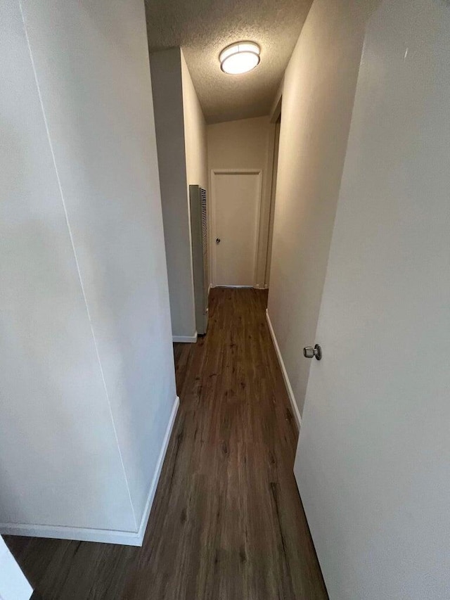 hall featuring dark wood-type flooring and a textured ceiling