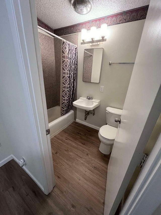 full bathroom with toilet, sink, shower / tub combo, a textured ceiling, and hardwood / wood-style flooring