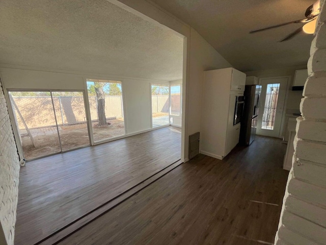 unfurnished living room featuring ceiling fan, a textured ceiling, and dark hardwood / wood-style flooring