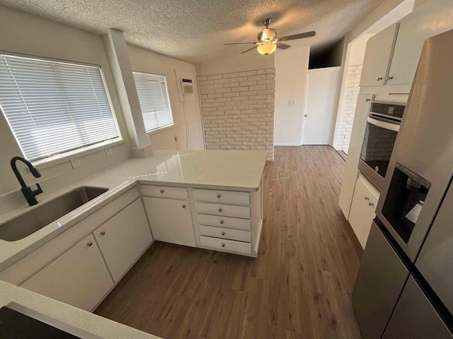 kitchen with sink, dark hardwood / wood-style floors, oven, and white cabinets