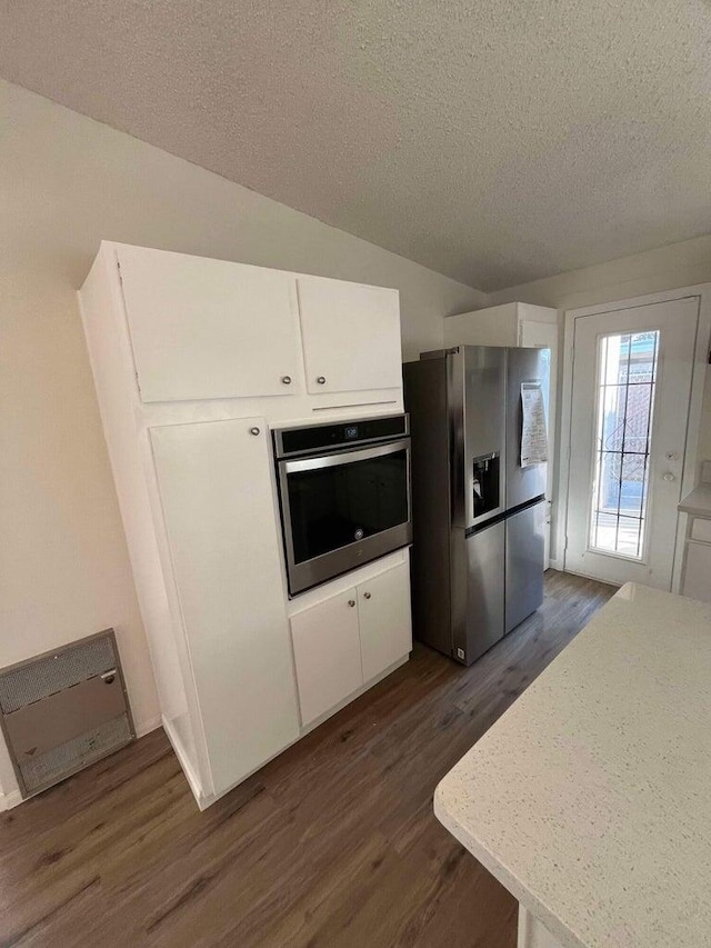 kitchen featuring a textured ceiling, dark hardwood / wood-style floors, white cabinets, and appliances with stainless steel finishes