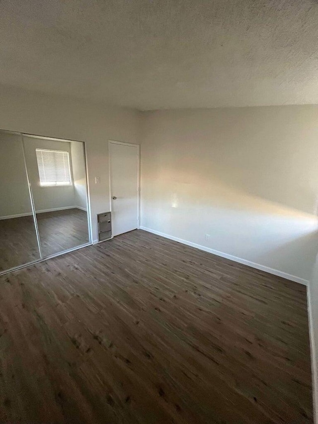 unfurnished bedroom featuring dark hardwood / wood-style floors, a textured ceiling, and a closet