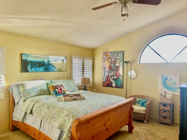 bedroom featuring light carpet, vaulted ceiling, and ceiling fan