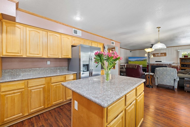 kitchen with light stone countertops, a center island, dark hardwood / wood-style floors, stainless steel refrigerator with ice dispenser, and crown molding