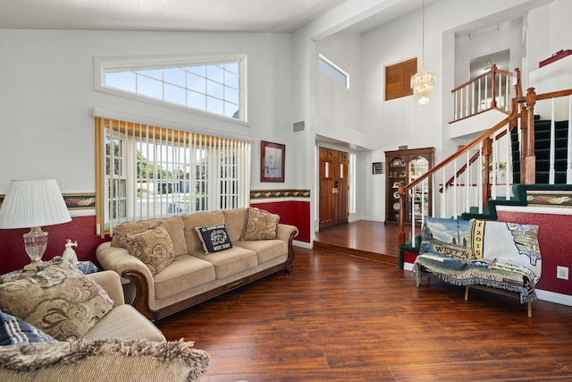 living room with a chandelier, a towering ceiling, and dark wood-type flooring