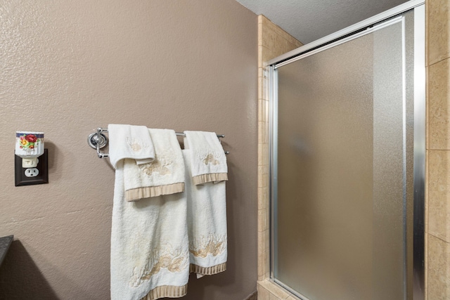 bathroom with a textured ceiling and a shower with door