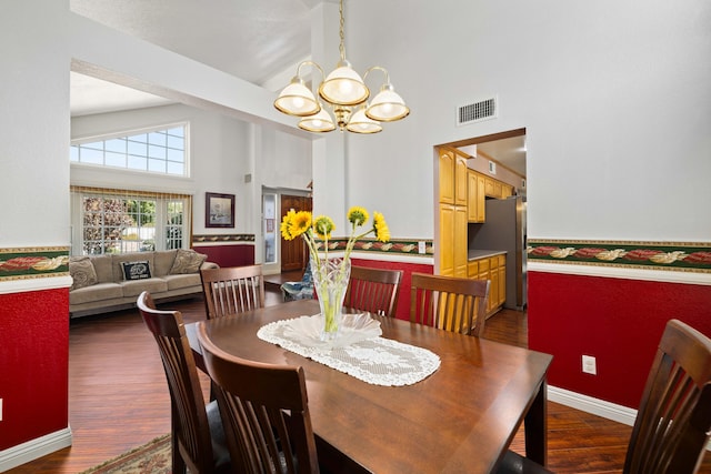 dining space featuring a notable chandelier, dark wood-type flooring, and high vaulted ceiling