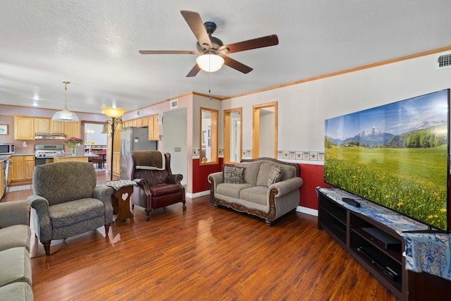 living room featuring a textured ceiling, ceiling fan, ornamental molding, and dark wood-type flooring