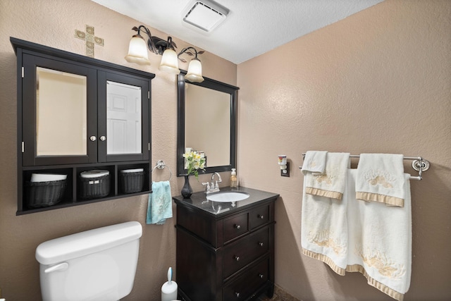 bathroom featuring vanity, a textured ceiling, and toilet