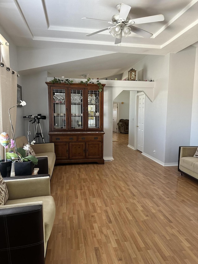 interior space featuring hardwood / wood-style flooring, a raised ceiling, and ceiling fan