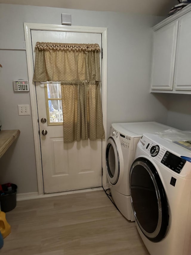 laundry room featuring washer and clothes dryer, cabinets, and light hardwood / wood-style floors