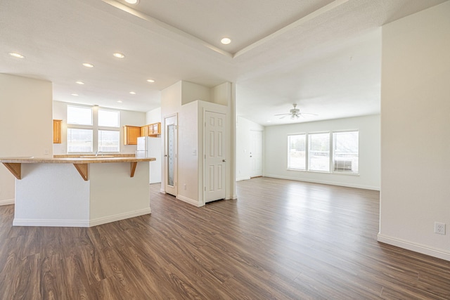 unfurnished living room with dark hardwood / wood-style floors, sink, and ceiling fan