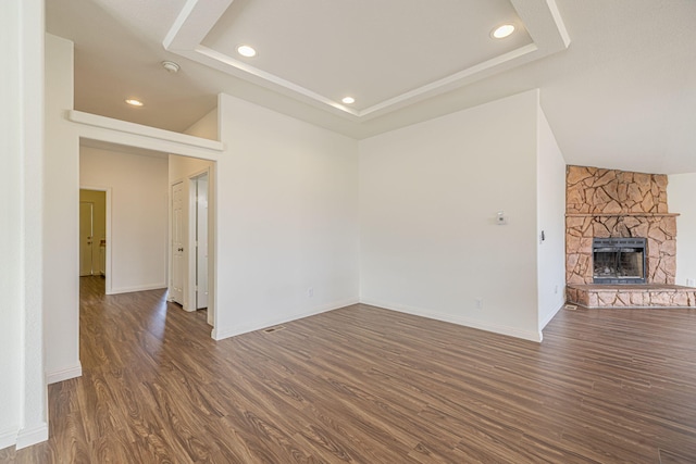 unfurnished living room featuring a fireplace, dark hardwood / wood-style flooring, and a raised ceiling