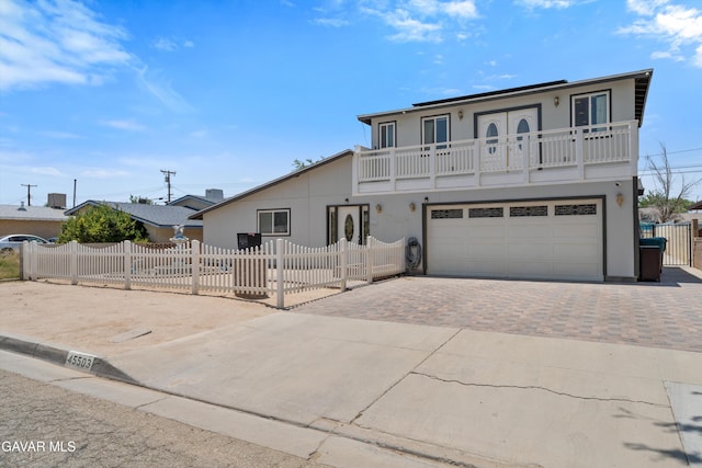 45503 Lorimer Ave, Lancaster, CA 93534 - view of front of property featuring a balcony, decorative driveway, stucco siding, a garage, and a fenced front yard