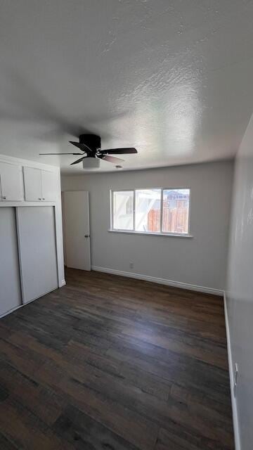 45526 Leatherwood Ave, Lancaster, CA 93534 - unfurnished bedroom with dark wood-type flooring, baseboards, a closet, and a ceiling fan