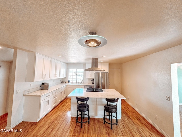 2895 59th St, Rosamond, CA 93560 - kitchen with stainless steel refrigerator, island exhaust hood, white cabinets, light wood-type flooring, and a textured ceiling