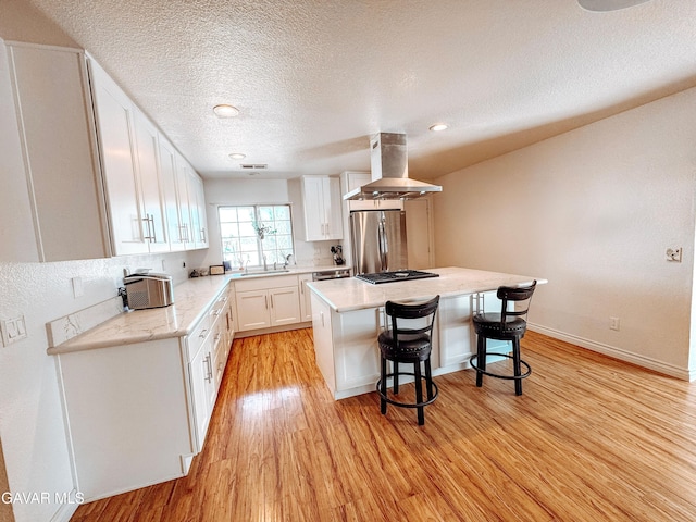 2895 59th St, Rosamond, CA 93560 - kitchen featuring exhaust hood, stainless steel refrigerator, a breakfast bar area, white cabinets, and light wood-style flooring