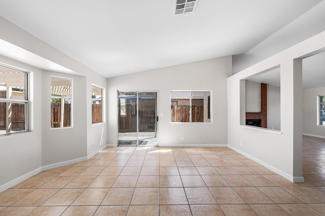 spare room with light tile patterned floors, visible vents, vaulted ceiling, and baseboards