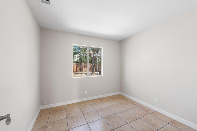 spare room featuring light tile patterned floors, visible vents, and baseboards