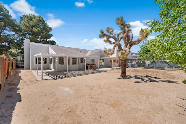 back of property with a pergola, a patio area, a chimney, stucco siding, and fence