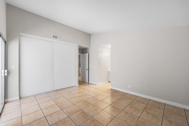 unfurnished bedroom with baseboards, visible vents, light tile patterned flooring, and a closet