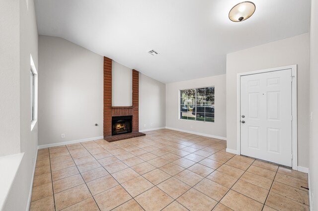 unfurnished living room featuring lofted ceiling, light tile patterned floors, visible vents, baseboards, and a fireplace