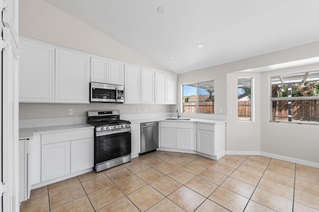 kitchen featuring lofted ceiling, a sink, appliances with stainless steel finishes, light countertops, and light tile patterned flooring