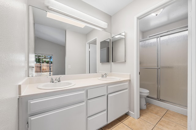 full bathroom with tile patterned floors, toilet, a shower stall, and a sink