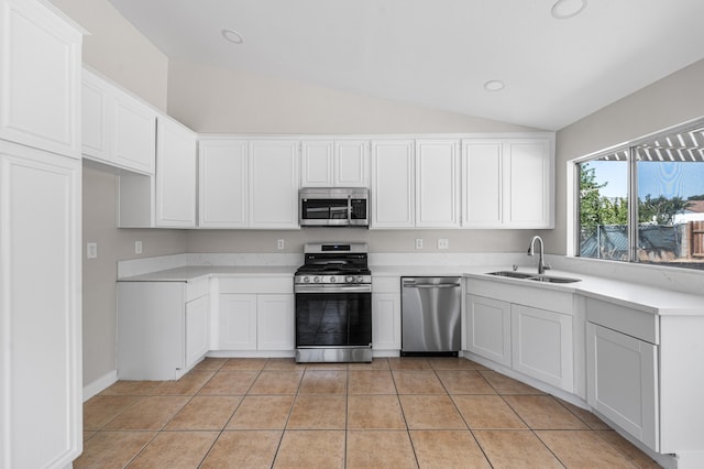 kitchen with a sink, stainless steel appliances, light tile patterned floors, light countertops, and lofted ceiling