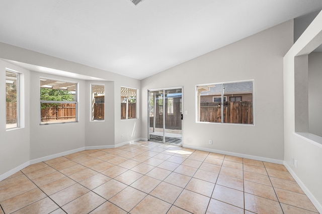 spare room with baseboards, a healthy amount of sunlight, tile patterned flooring, and vaulted ceiling