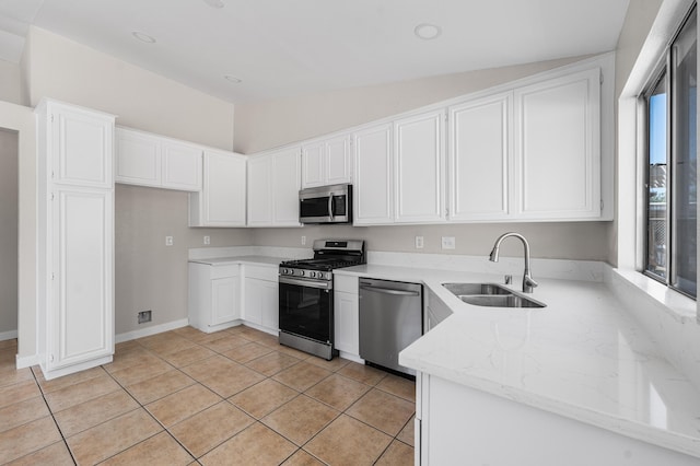 kitchen with light stone countertops, stainless steel appliances, white cabinets, and a sink