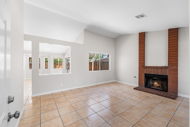 unfurnished living room featuring light tile patterned floors, visible vents, a brick fireplace, and vaulted ceiling