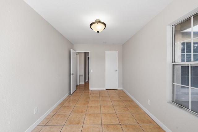 corridor with baseboards and light tile patterned floors