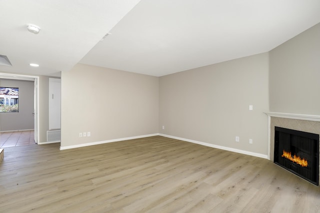 43334 W 32nd St Unit 12, Lancaster, CA 93536 - unfurnished living room featuring a tile fireplace, light wood finished floors, and baseboards