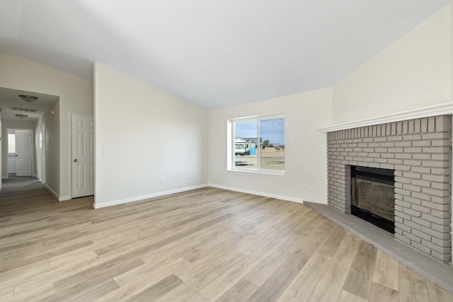 unfurnished living room with light wood-style floors, a fireplace, vaulted ceiling, and baseboards