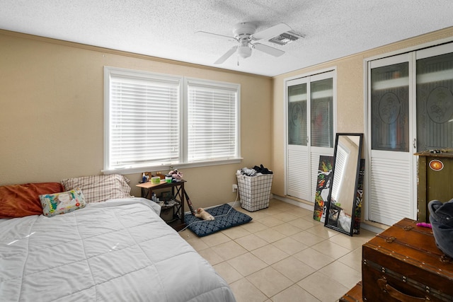 tiled bedroom featuring a textured ceiling, two closets, ceiling fan, and ornamental molding