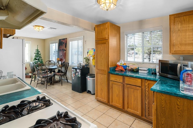 kitchen with light tile patterned floors, white refrigerator, plenty of natural light, and sink