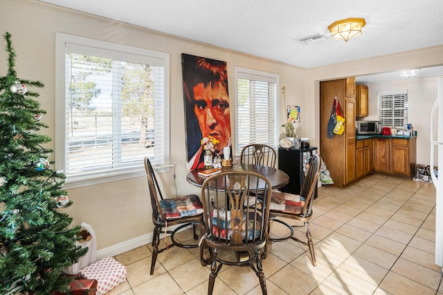 tiled dining space featuring a textured ceiling, a wealth of natural light, and crown molding