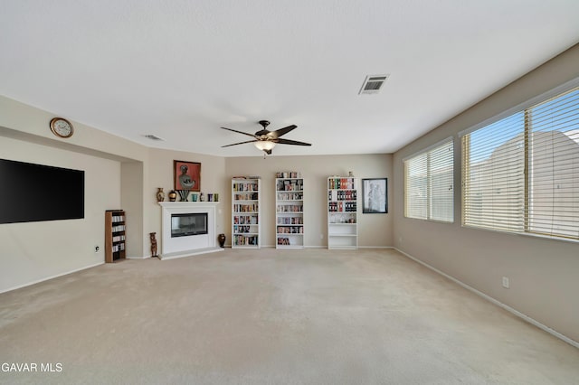 2354 Crimson Ave, Rosamond, CA 93560 - unfurnished living room featuring carpet flooring, a ceiling fan, and a glass covered fireplace