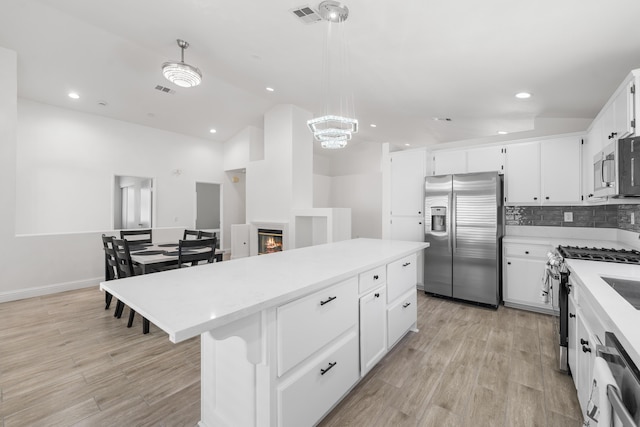 37116 Alder St, Palmdale, CA 93552 - kitchen featuring appliances with stainless steel finishes, lofted ceiling, light countertops, light wood-type flooring, and a kitchen island