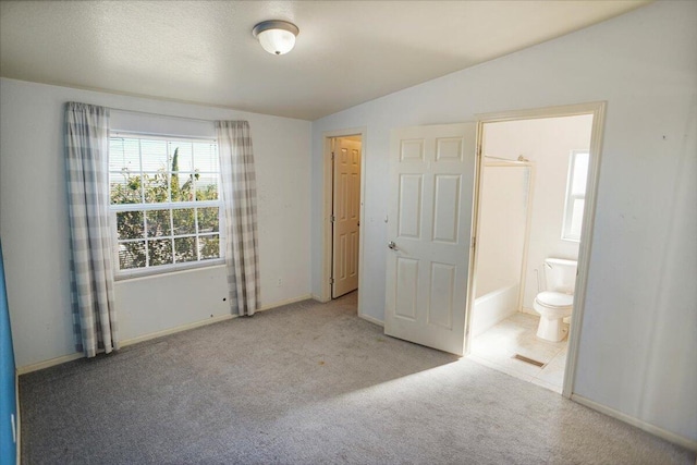 unfurnished bedroom with connected bathroom, light carpet, a closet, and vaulted ceiling