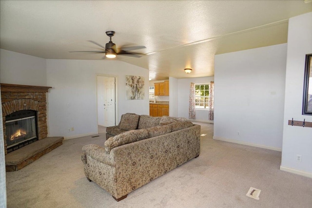 living room with ceiling fan, a fireplace, light carpet, and vaulted ceiling