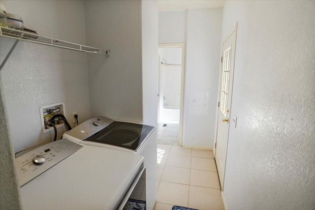 clothes washing area with independent washer and dryer and light tile patterned floors