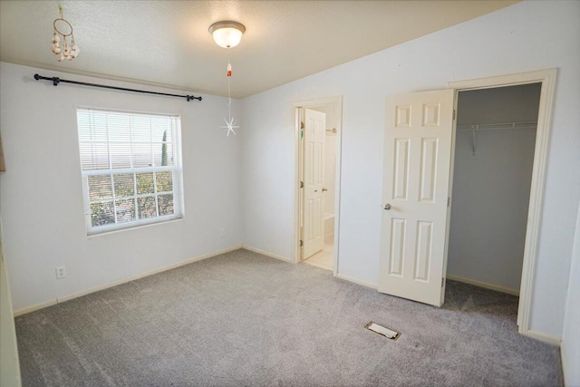 unfurnished bedroom featuring carpet floors, ensuite bath, a closet, and lofted ceiling