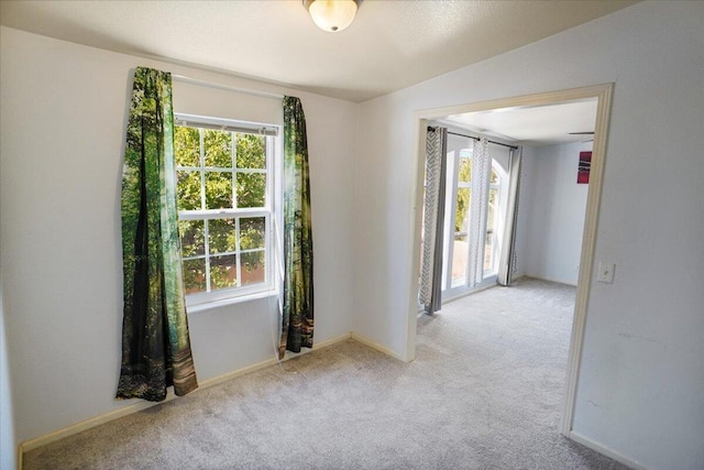 spare room with lofted ceiling and light carpet