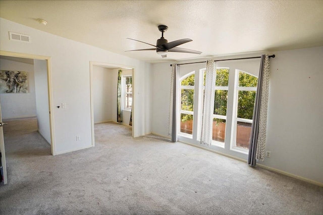 carpeted empty room with a textured ceiling, vaulted ceiling, and ceiling fan