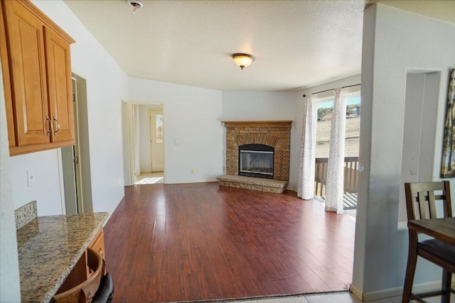 living room with a textured ceiling, a fireplace, and dark wood-type flooring