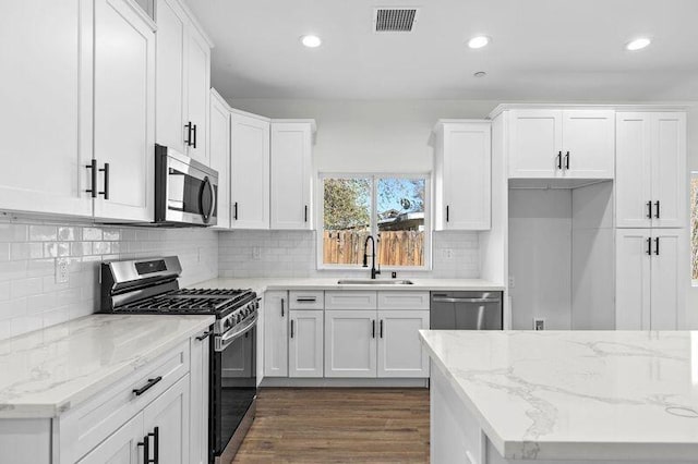 kitchen featuring decorative backsplash, white cabinetry, sink, and appliances with stainless steel finishes