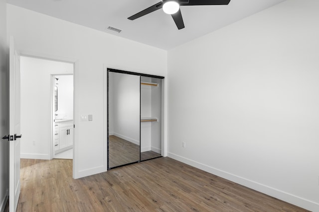 unfurnished bedroom with ceiling fan, a closet, and hardwood / wood-style floors